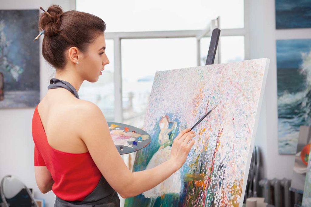 Woman paints a picture during expressive therapy