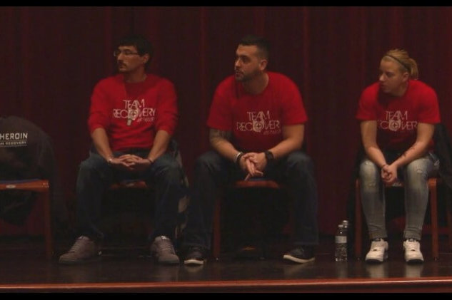three people with team recovery shirts on sitting in a row