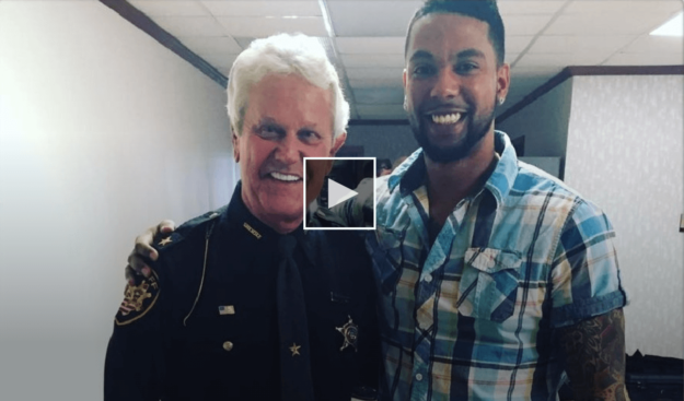 screenshot of man standing next to a police officer