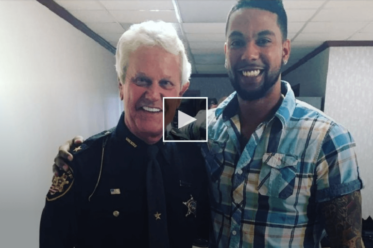 screenshot of man standing next to a police officer