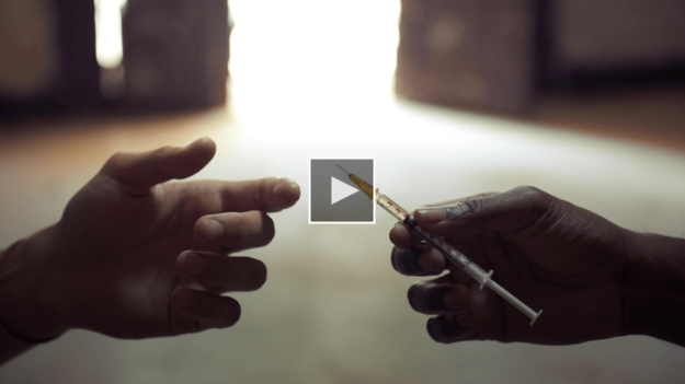 screenshot of person holding a syringe