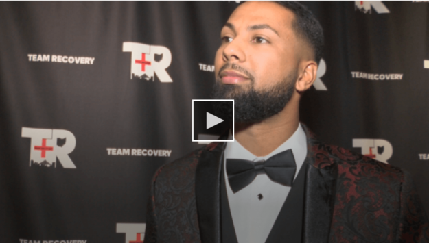 screenshot of man standing in front of team recovery logo