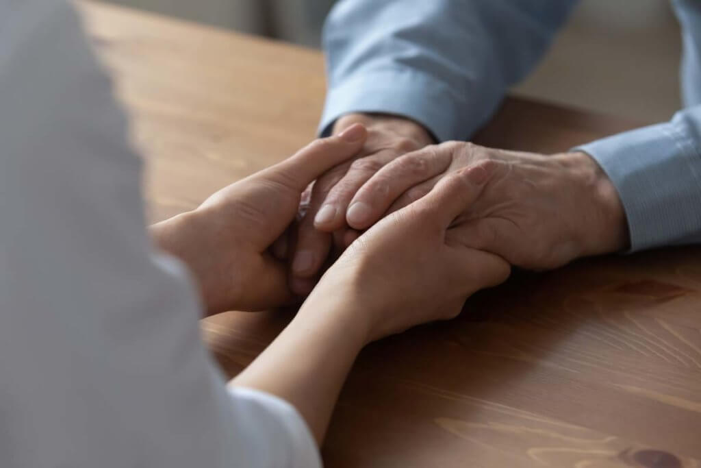 woman holding her father's hands wondering Does My Loved One Need a Detox Center