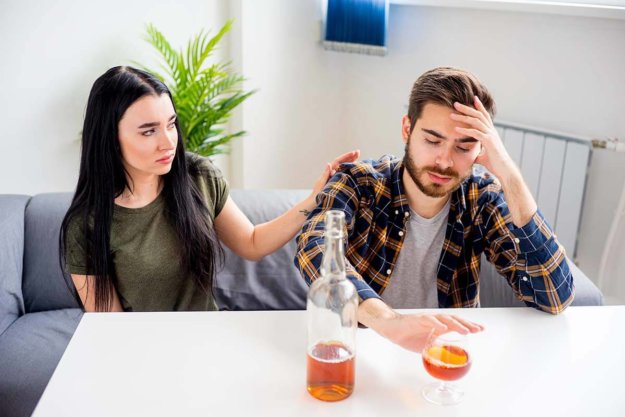 how to help an alcoholic woman putting a hand on her drinking husband wondering How to Help an Alcoholic