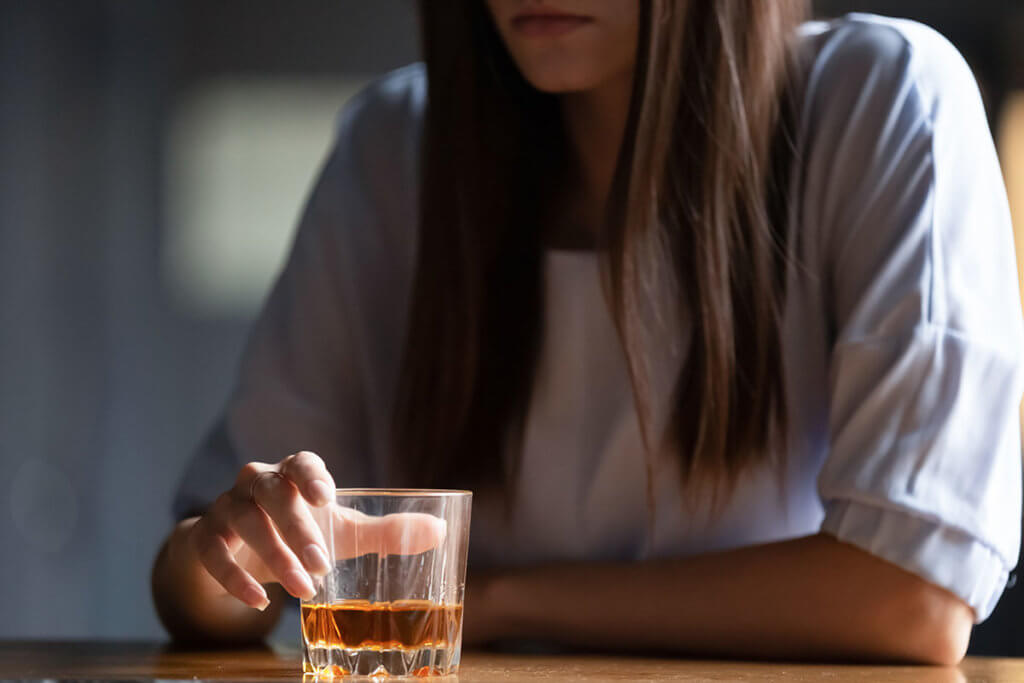 woman with a glass of alcohol wondering Is Alcohol a Drug