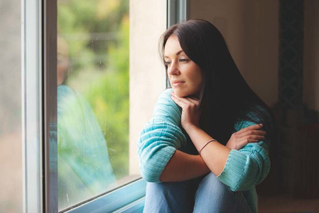 woman gazing out a window thinking about What to Expect During Detox