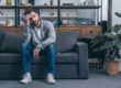 a man sitting on a couch thinking about heroin withdrawal symptoms