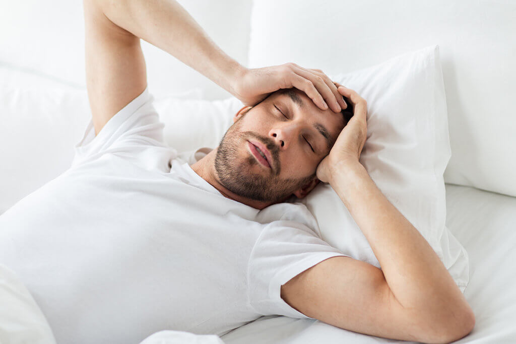 man holding his head in bed wondering Can You Die from Heroin Withdrawal
