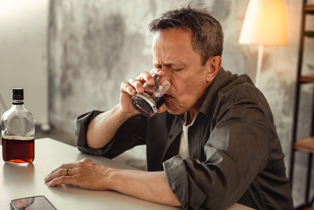 man drinking a glass of alcohol despite thinking Is Alcohol a Depressant
