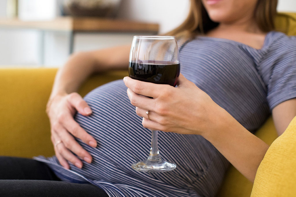 woman holding glass of wine for drinking while pregnant