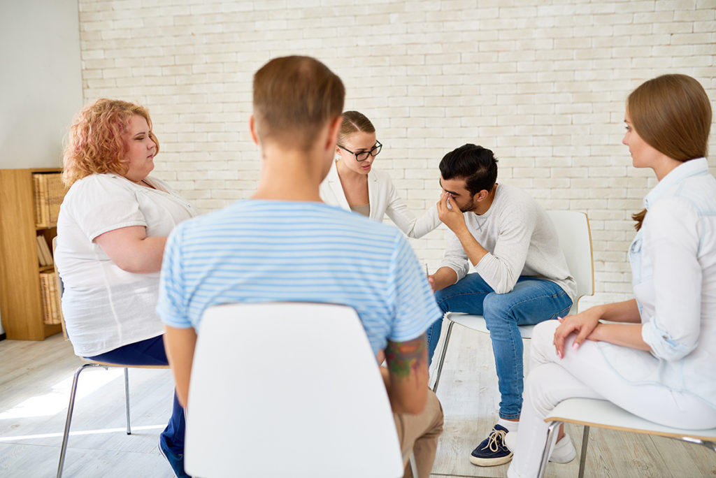 group tells a man about what to expect at his recovery center
