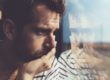 a man looking out a window thinking about the signs of a xanax addiction