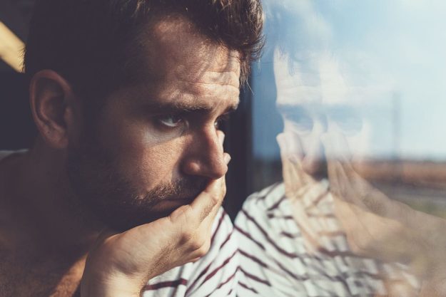 How to Spot a Xanax Addiction a man looking out a window thinking about the signs of a xanax addiction