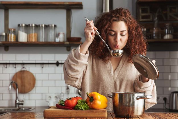 Photo of pretty caucasian woman holding cooking ladle spoon whil woman cooks food that will speed her recovery