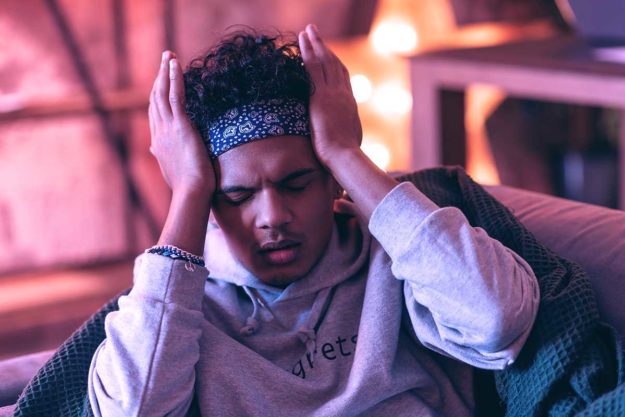 Poor boy having a relapse of a severe headache that he suffers from. man struggles with the signs of relapse