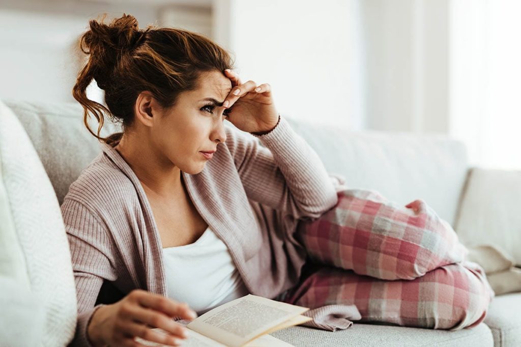 a woman sitting on her couch thinking about opiate withdrawal timelines