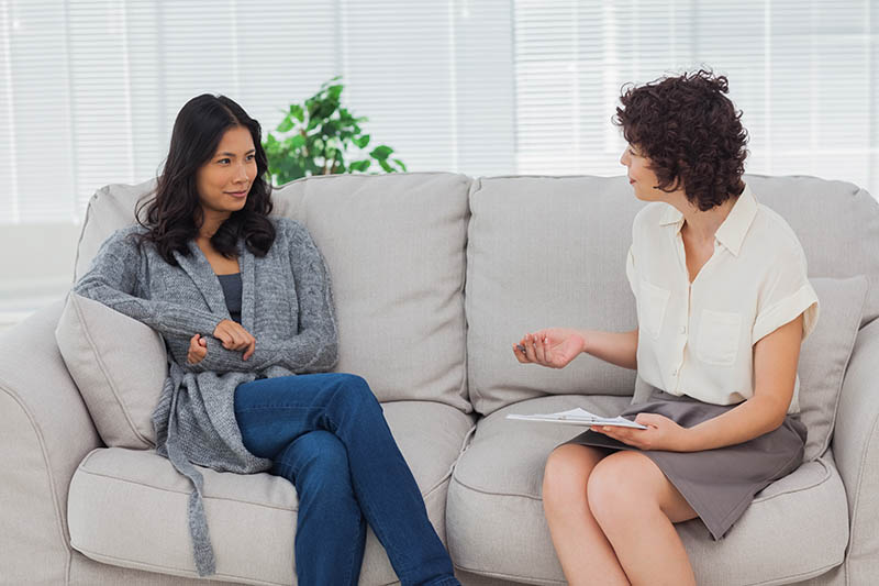 women sits on couch with therapist as they talk about medication assisted treatment