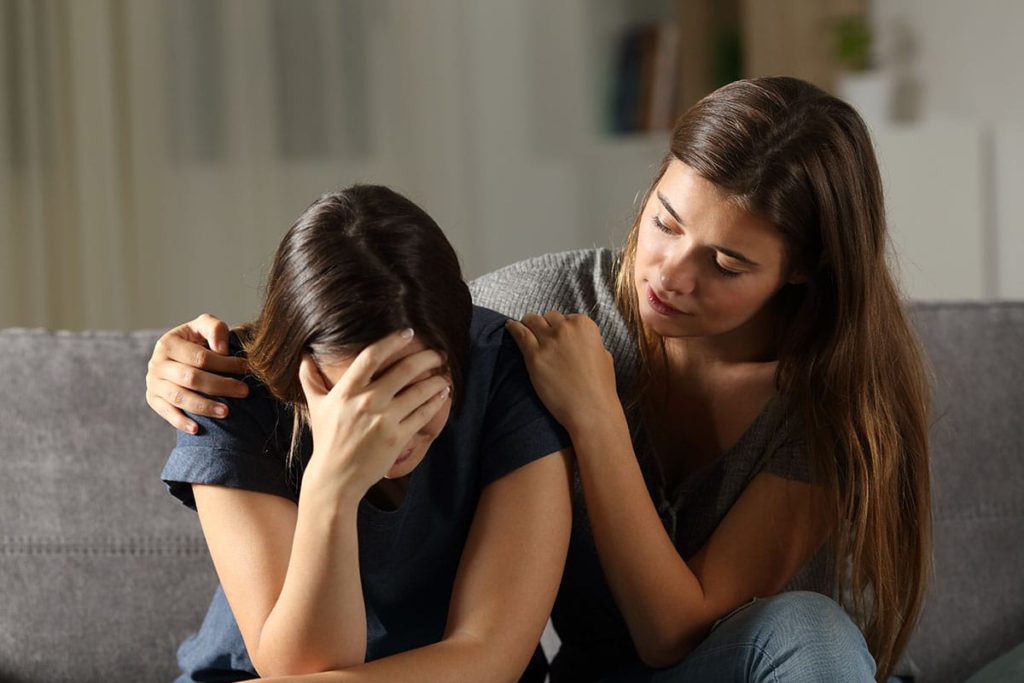 a woman displaying signs of fentanyl addiction being comforted by her friend