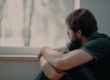 a man looking out a window wondering is marijuana addictive