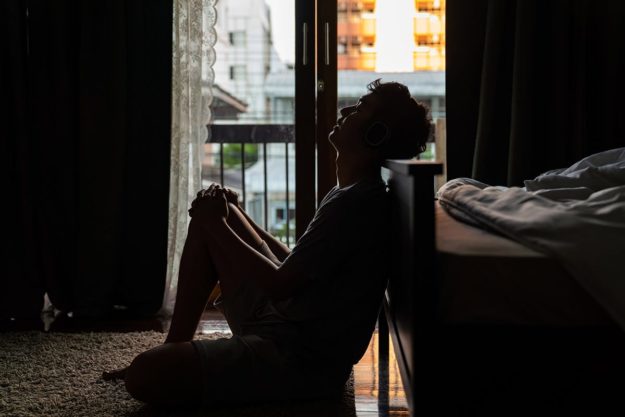 What to Know About Adderall Withdrawal man sitting on the floor suffering from adderall withdrawal symptoms